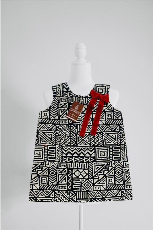 Black and white geometric patterned dress with red accents on a mannequin against a gray background