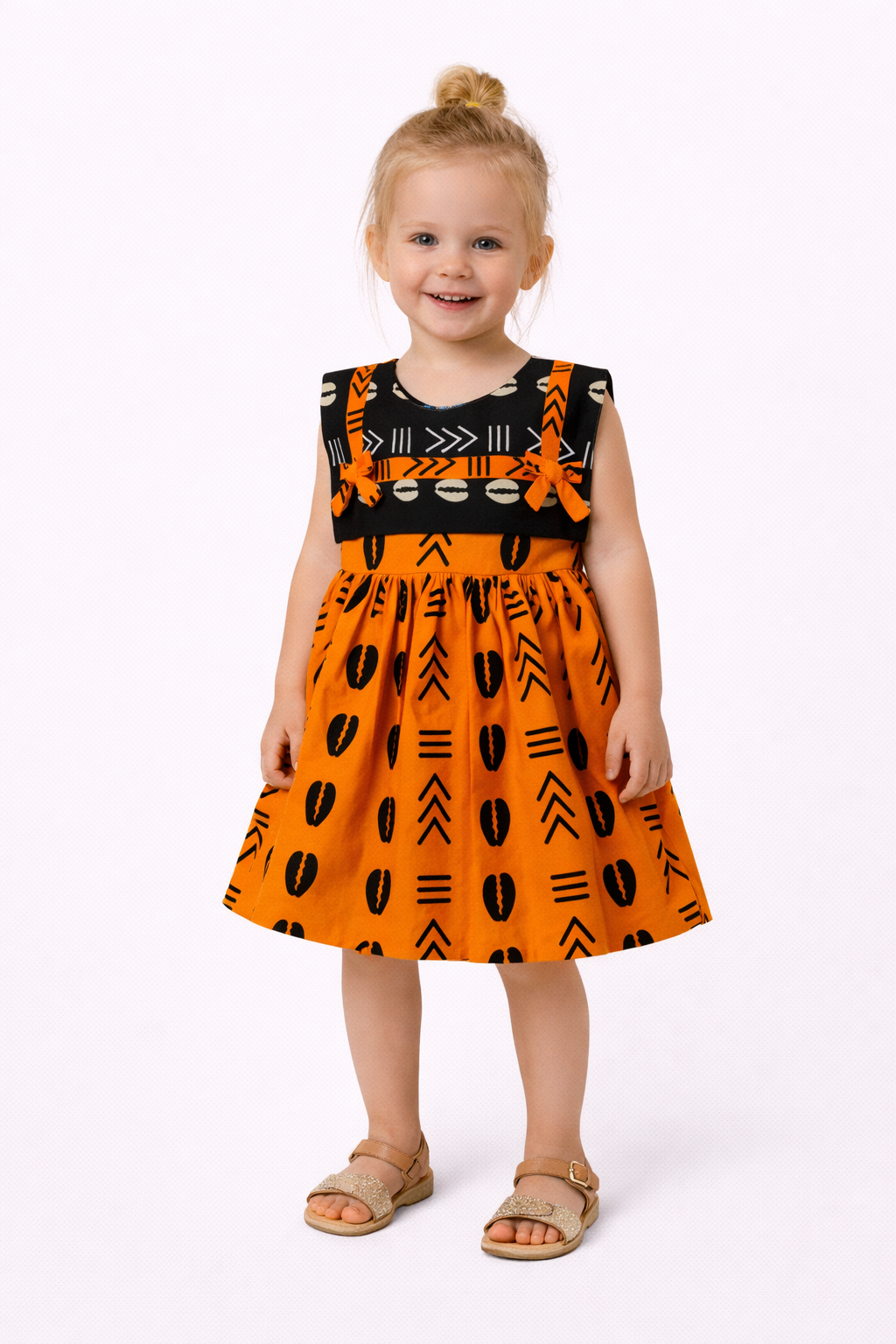 Child wearing an orange dress with black patterns on a white background